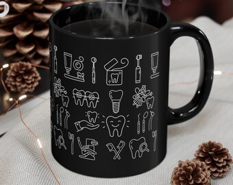 May include: Black coffee mug with a white outline of dental tools and teeth. The mug is filled with coffee and steam is rising from the top.