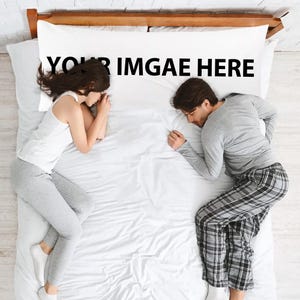 May include: A top view of a couple sleeping in a white bed with a white pillow that says "YOUR IMGAE HERE".