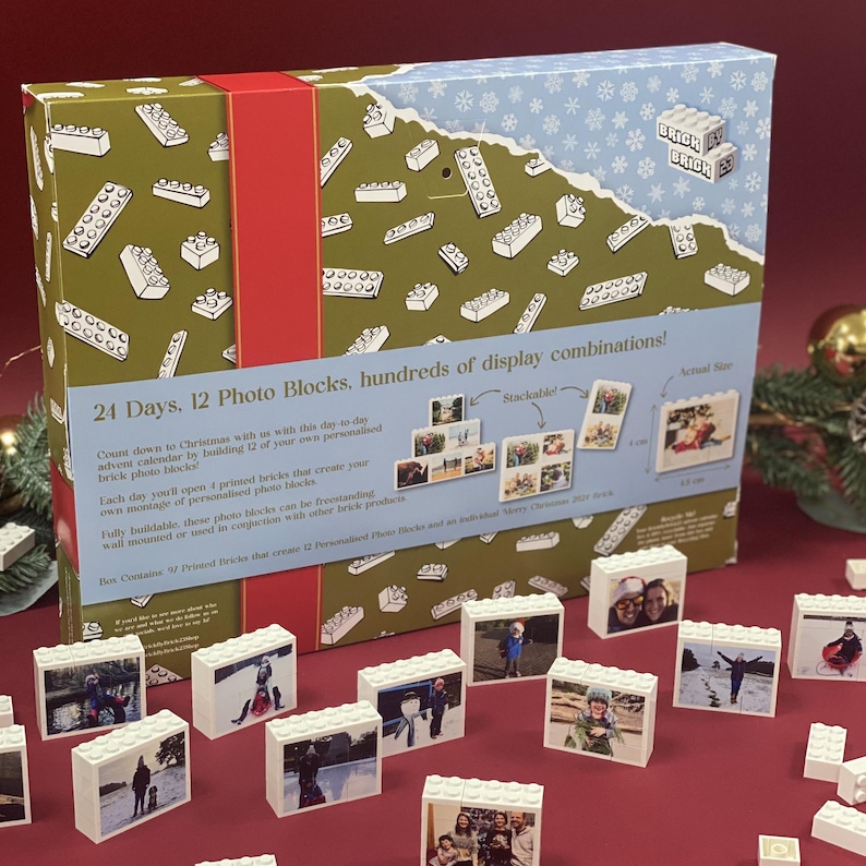 May include: A green and blue box with a white snowflake pattern. The box is labeled "Brick by Brick" and features a 24-day advent calendar with 12 photo blocks. The back of the box shows examples of how to stack the blocks and includes the text "24 Days, 12 Photo Blocks, hundreds of display combinations!"