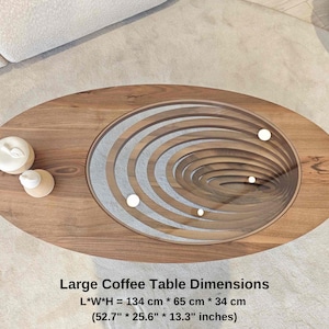 May include: A large oval coffee table with a unique design featuring concentric circles of wood and a glass top. The table is made of wood and has a natural finish. The table measures 52.7 inches long, 25.6 inches wide, and 13.3 inches high.