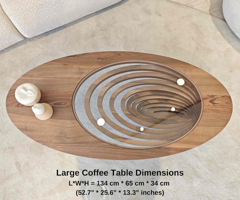 May include: A large oval coffee table with a unique design featuring concentric circles of wood and a glass top. The table is made of wood and has a natural finish. The table measures 52.7 inches long, 25.6 inches wide, and 13.3 inches high.