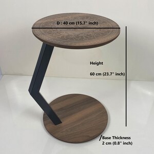 May include: A round side table with a dark wood top and base, supported by a black metal frame. The table top is 40 cm in diameter and has an etched pattern. The table stands 60 cm tall, with a base thickness of 2 cm.
