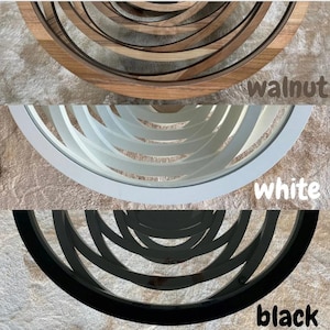 May include: Three round coffee tables with different finishes: walnut, white, and black. Each table has a unique design with concentric circles.