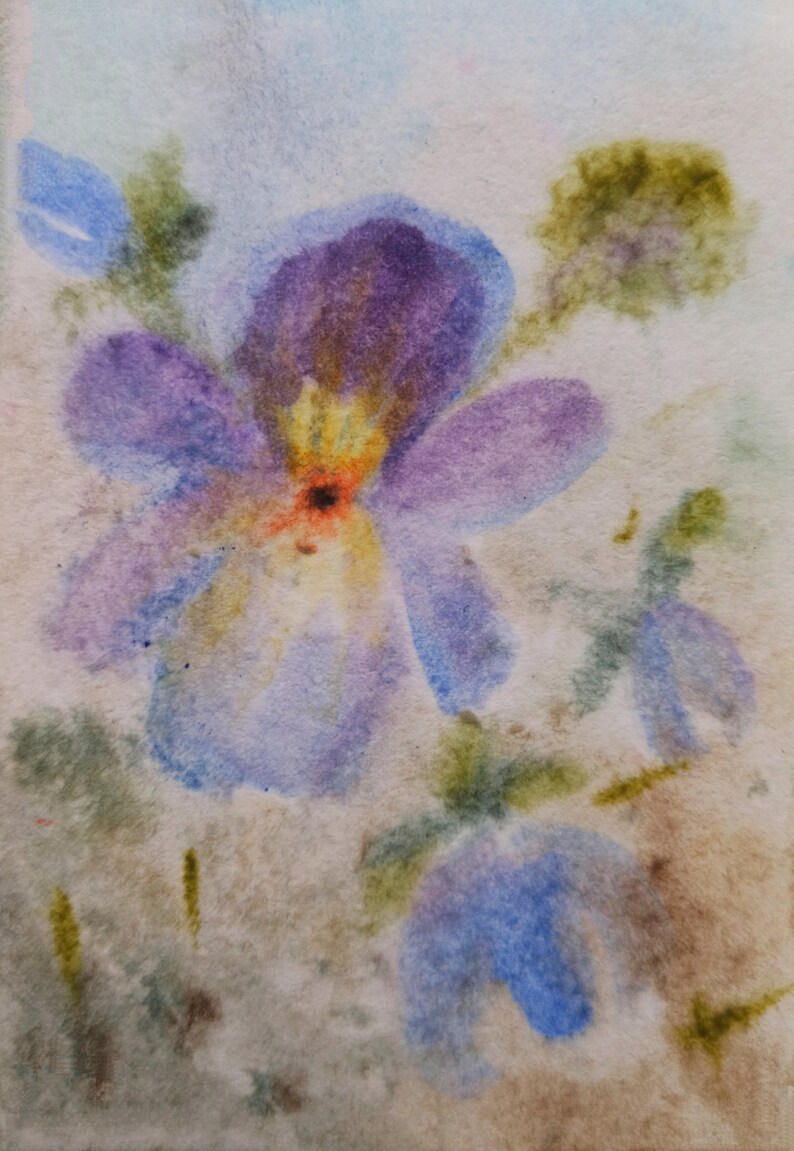 May include: Watercolor painting of a purple and blue flower with yellow and orange accents. The flower is painted on a light brown background.