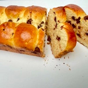 May include: A loaf of brioche bread with chocolate chips, sliced into three pieces. The bread is golden brown and has a slightly crispy crust.