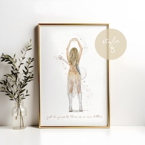 May include: A framed art print featuring a blonde figure seen from behind, wearing a gold fringed dress and white boots, holding a guitar and making a heart shape with hands. The text reads, "just be yourself. there is no one better."