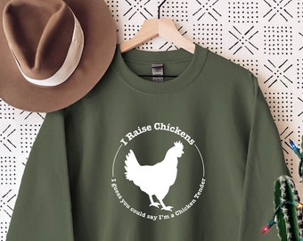 Może przedstawiać: Zielony sweter z białym nadrukiem przedstawiającym kurczaka i tekstem "I Raise Chickens I guess you could say I'm a Chicken Tender".