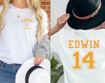 May include: Two white t-shirts with the name "EDWIN" printed on them. One shirt has a hockey stick graphic and the other has the number "14" printed on the back.