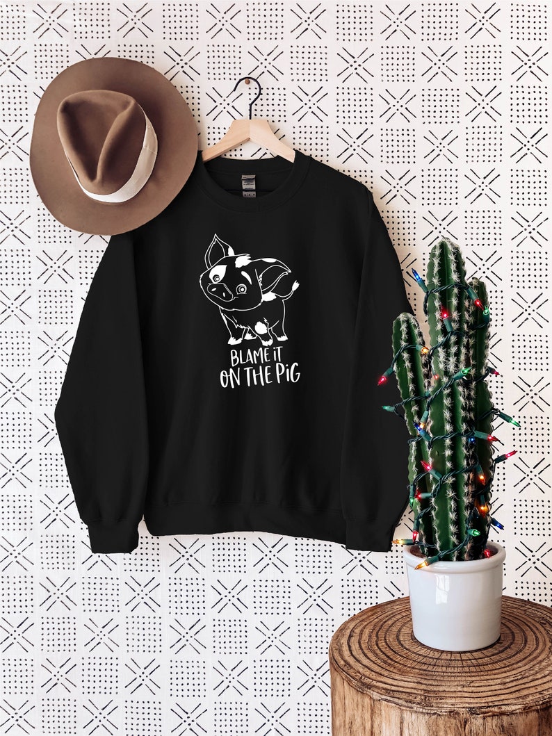 Puede incluir: Sudadera negra con un gr&aacute;fico blanco de un cerdo de dibujos animados y el texto "Blame it on the pig".