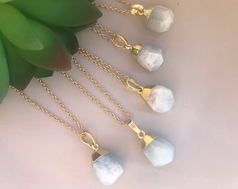 May include: Five gold necklaces with light blue gemstone pendants. Each pendant is a faceted, irregular shape.