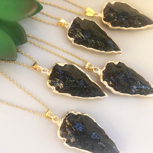 Pode incluir: Cinco colares de ouro com pingentes de ponta de flecha de obsidiana preta. As pontas de flecha s&atilde;o todas de formas e tamanhos diferentes.
