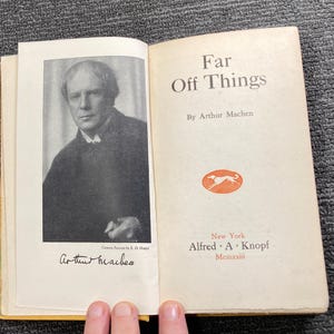 May include: Open book titled "Far Off Things" by Arthur Machen. The left page features a black and white portrait and signature. The right page displays the title, author, and publisher information, including "New York Alfred A. Knopf Mcmxxiii".