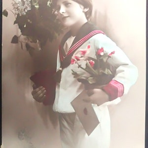 Postal con matasellos de 1913 que representa a un niño con ramos de flores y una carta de Año Nuevo en la mano. Tarjeta para año nuevo