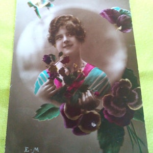 Dame met art deco kapsel en Parijse modekleding afgebeeld in een medaillon en omring door bloemenpracht. Jaren 20, Franse kaart