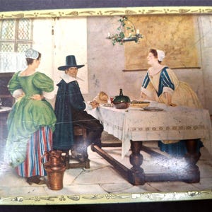 May include: Vintage metal serving tray with a painted scene of people in historical clothing gathered around a table. The tray has a decorative border with a floral design and a yellow background.
