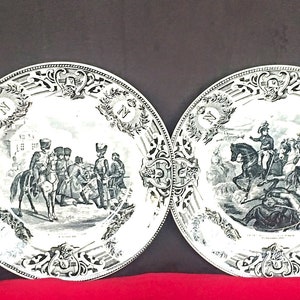 May include: Set of four black and white porcelain plates with a decorative border and a central image of a horse race. Each plate features a different scene from the race.