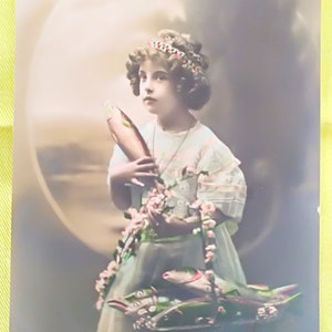 Carte postale française du 1er avril, avec Jeune fille avec une belle coiffure et un bandeau, un panier décoré de roses et plein de poissons d'avril colorés