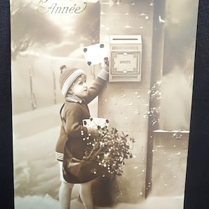 Postal de Año Nuevo, con un niño en un paisaje nevado poniendo una carta en el buzón. Bonito sombrero y ropa. Bolsa con flores