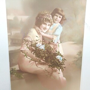 Tarjeta francesa de Año Nuevo, Bonne Année, usada y enviada con texto en alemán, Dama e hija con hermosos vestidos y ramo de flores.