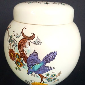 May include: White ceramic jar with a lid, featuring a blue bird with brown and green floral accents.