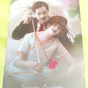 Postal francês da década de 1920 com um casal romântico com sombrinha, lindas roupas e um lindo texto na parte inferior do cartão "Tendre Causerie"