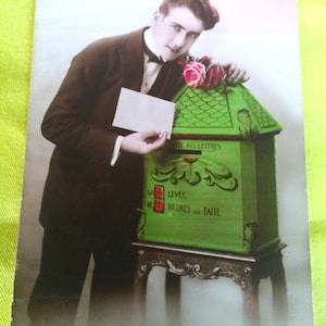 Postal francesa de los años 1920; Un hombre de moda se apoya en el buzón y sostiene en la mano una carta de amor que quiere enviar. Tarjeta art déco