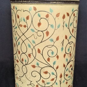 Op de afbeelding: Een vintage crèmekleurige metalen bus met een bruine rand en een teal en oranje bloemenpatroon.
