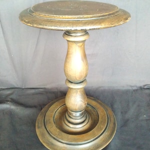 Op de afbeelding: Een donkerbruine houten sokkeltafel met een rond blad en een enkele, gegroefde kolom. De tafel heeft een eenvoudig, elegant ontwerp.