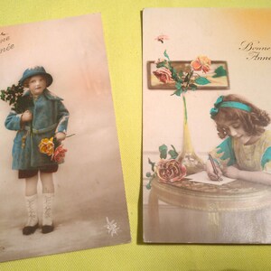Conjunto de 1923 de dois cartões postais antigos franceses coloridos de Ano Novo, cartões postais românticos, meninas com roupas da Belle Époque com flores