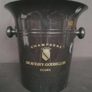 Op de afbeelding: Zwarte plastic champagne-emmer met gouden opschrift "Champagne Dravigny-Godbillon Ecuiel".