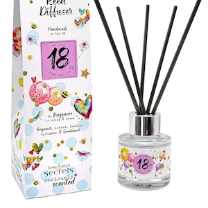 May include: A white gift box with a colourful illustration of balloons and hearts. The box has the text "Just Because... Reed Diffuser" and "on your 18th Just for you". The box is next to a clear glass bottle with a silver lid and black reed sticks. The bottle has a label with the text "on your 18th Just for you".