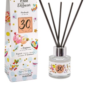 May include: A white gift box with a colorful illustration of hearts, balloons, and bees. The box says "Just Because... Reed Diffuser Handmade in the UK On Your 30th Just For You". The box is next to a clear glass bottle with a silver lid and black reeds. The bottle has a colorful label with the text "On Your 30th Just For You".