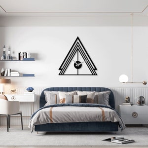 May include: A modern bedroom with a blue velvet headboard bed, a white desk with a chair, and a black geometric wall clock. The room has a white ceiling with a decorative molding, white walls, and a white rug.