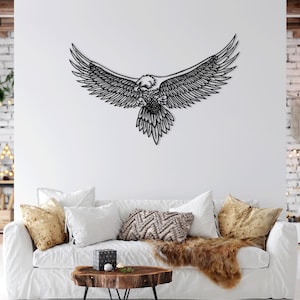 Könnte beinhalten: Schwarze Wandskulptur aus Metall, die einen Adler mit ausgebreiteten Flügeln darstellt. Der Adler ist im Flug und hat ein detailliertes Design. Die Skulptur ist an einer weißen Wand in einem Wohnzimmer angebracht.