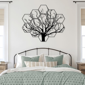 Puede incluir: Arte de pared de metal negro con un árbol con ramas en un diseño de panal. El arte está colgado en una pared blanca sobre una cama con una colcha de patrón verde.