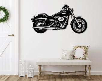 May include: Black metal silhouette of a motorcycle with a white wall behind it. The motorcycle is on a white wall with a white door and a white bench in the foreground.