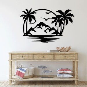 May include: Black metal wall art depicting a tropical scene with palm trees, mountains, and a sun. The art is mounted on a white wall above a wooden console table.