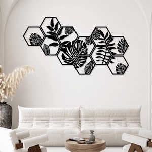 May include: A wall decor set featuring eight black metal hexagonal shapes with cut-out leaf designs. The shapes are arranged in a staggered pattern, creating a modern and stylish look.