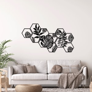 May include: Black metal wall decor featuring a geometric design of hexagonal shapes with cut-out tropical leaf patterns.