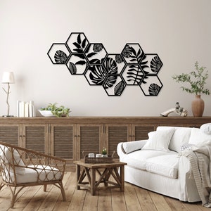 May include: Black metal wall decor featuring a geometric design of hexagonal shapes with cut-out silhouettes of tropical leaves.