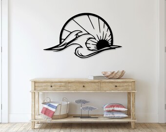 May include: Black metal wall art depicting a stylized wave crashing over a sun. The sun has rays emanating from it. The art is mounted on a white wall above a wooden console table.