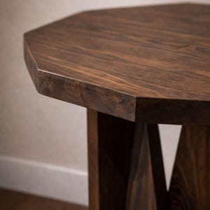 Close-up of octagonal top and beveled edge, dark walnut grain visible on handmade wood end table pedestal.