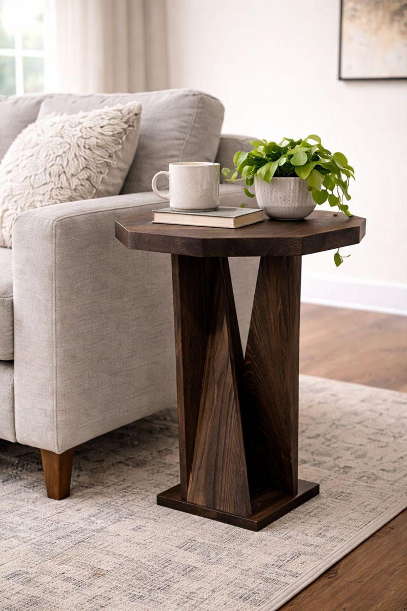 Compact small wooden side table in dark rustic-modern finish, beside gray sofa with plant and coffee mug.