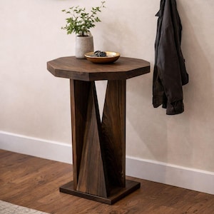 Small wooden side table placed under round mirror, twisted geometric pedestal visible, styled in entryway.