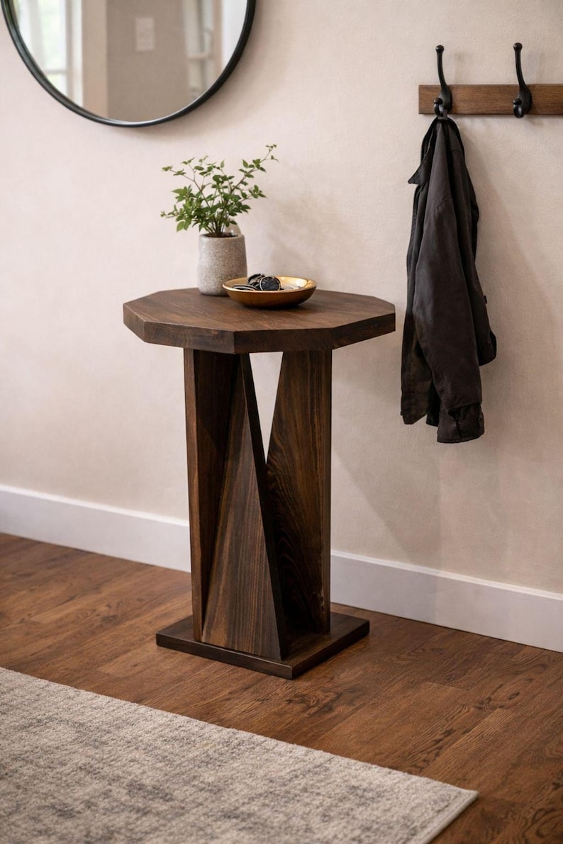 Small wooden side table placed under round mirror, twisted geometric pedestal visible, styled in entryway.
