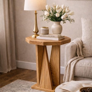 Natural finish small wooden side table as handmade bedside table, lamp and vase on narrow small space furniture.