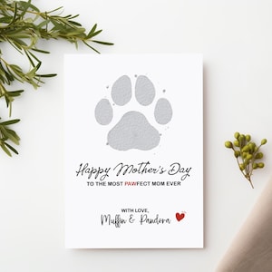 May include: A white card with a gray paw print and the text "Happy Mother's Day to the most pawfect mom ever."  The card also includes the text "With love, Muffin & Pandora" and a small red heart.