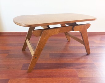 May include: A wooden coffee table with a rectangular top and a unique, angled, four-legged base.