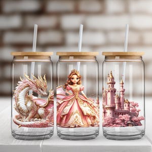 May include: Three glass tumblers with lids and straws. Each tumbler features a different design: a pink dragon, a princess in a pink gown, and a pink castle.