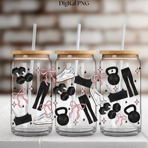 May include: Three glass tumblers with bamboo lids and straws, decorated with fitness-themed illustrations. Each tumbler features images of dumbbells, trainers, sports bras, leggings, and kettlebells, accented with pink bows and stars.